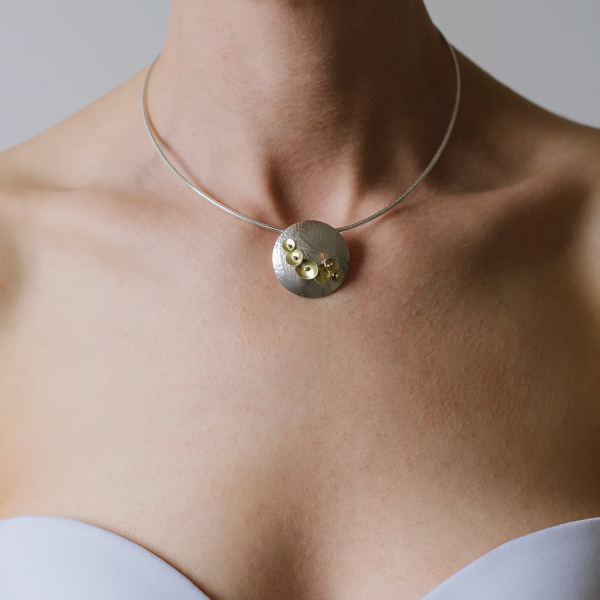 Model wearing Bloom pendant silver and 22ct gold.
