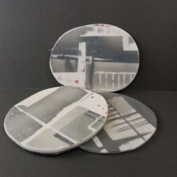 Three white and grey parian porcelain coasters on grey background