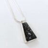 Silver pendant set with black tile on white background