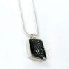 Silver pendant set with black tile on white background