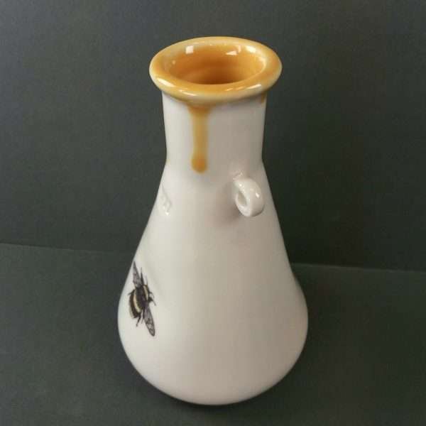 Porcelain bottle with bee decal on grey background