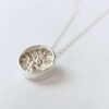 Round silver pendant with granulated details inside on silver chain