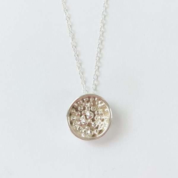 Round silver pendant with granulated details inside on silver chain