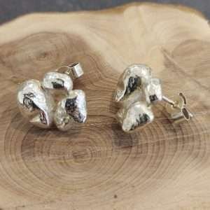 textured silver stud earrings on wooden display