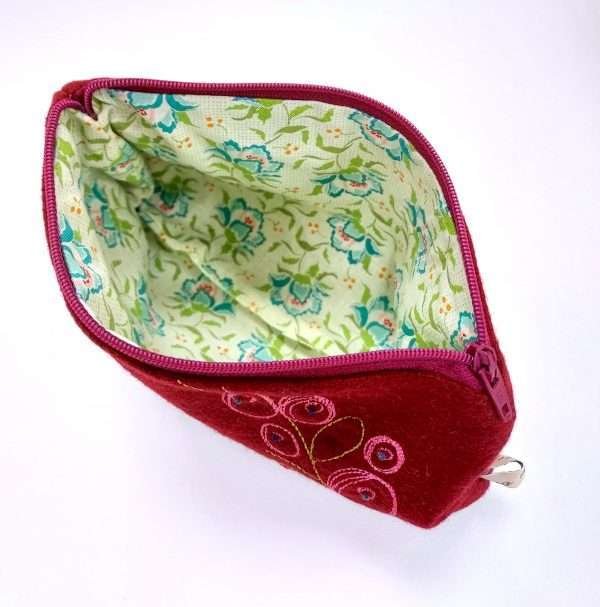 Inside green pattern lining of aRed / pink embroidered textile pouch with zip
