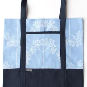 A linen tote bag printed with an elderflower pattern in white and blue with navy handles and base