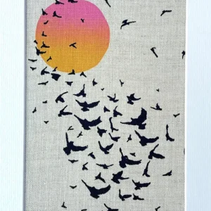 print of starlings in black with and orange and pink sun in a white mount