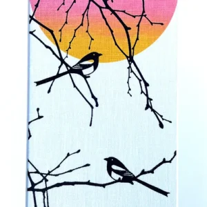 Print of two magpies on branches, printed in black with a pink and orange sun behind. set in a white mount